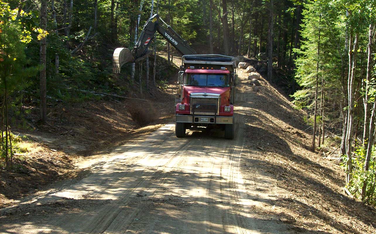 Long road/driveway construction in wooded area. Maine